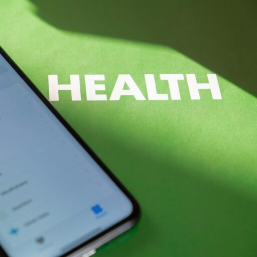 Close-up of a smartphone displaying a health app on a green surface with 'HEALTH' text.